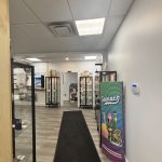 Bright cannabis retail interior with glass display cases, product shelves, and spinach brand banner