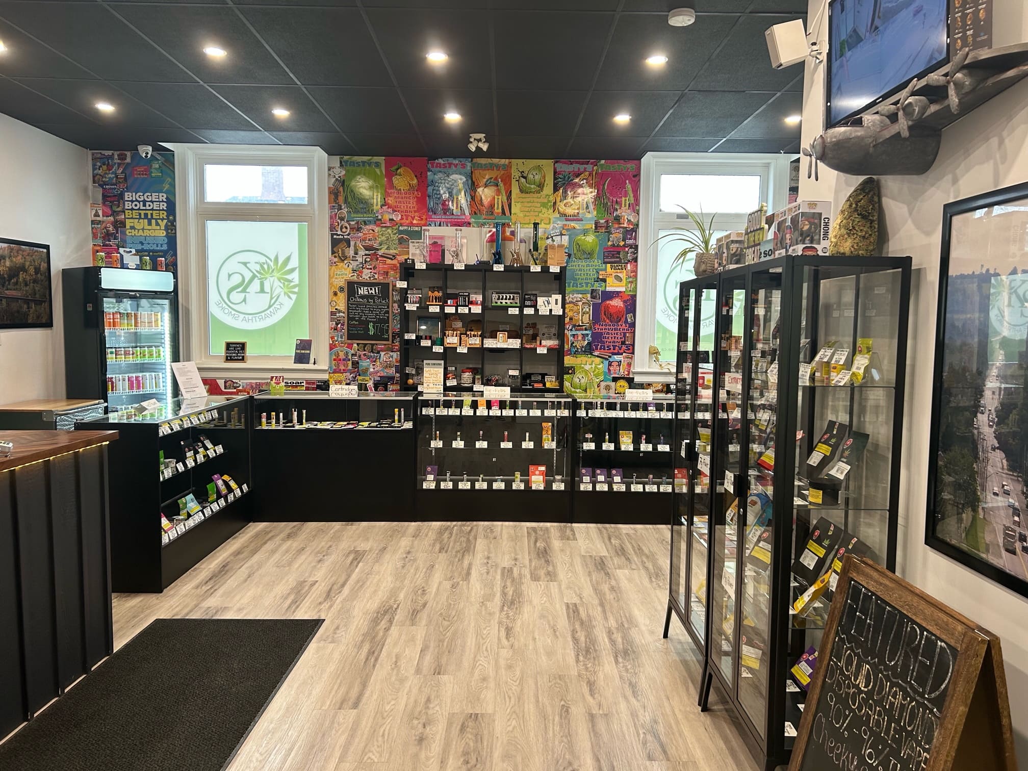 Bright cannabis retail interior with glass display cases, product shelves, and logo decals on the windows